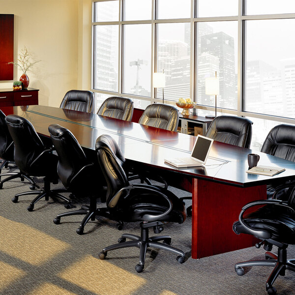 A Safco cherry conference table with black leather chairs in a conference room.