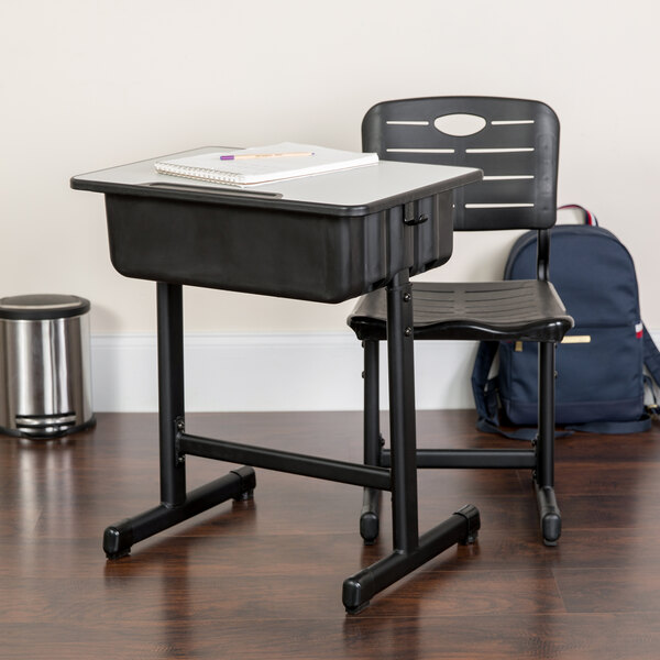 A black Flash Furniture school desk and chair with a notebook on top.
