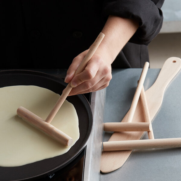 A person using Fox Run beechwood crepe batter spatula and spreaders to make crepes.