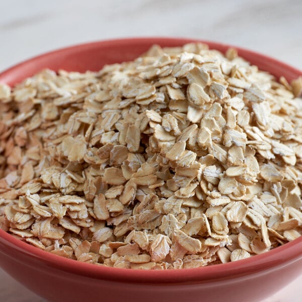 A bowl of Bob's Red Mill organic whole grain oat flakes on a table.