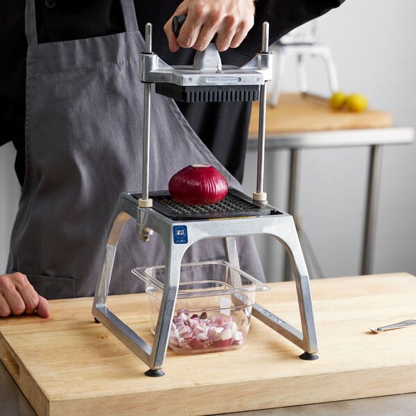 A person using a Vollrath vegetable dicer to cut onions on a cutting board.