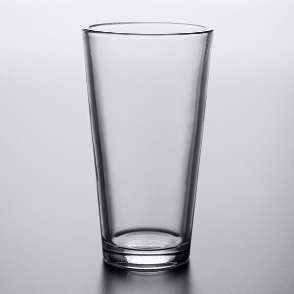 An Arcoroc clear tempered mixing glass on a table.