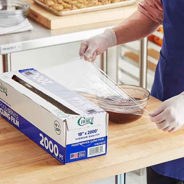 A person wrapping a box of Choice Foodservice Film with a serrated cutter.