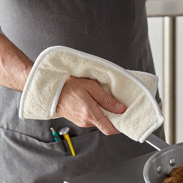 A person using a white terry cloth pan grabber to hold a pan.