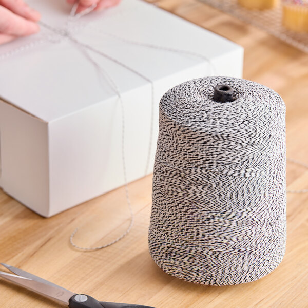 A large cone of black and white variegated polyester cotton blend baker's twine.