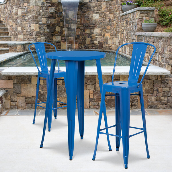 A blue metal bar height table with two blue stools.
