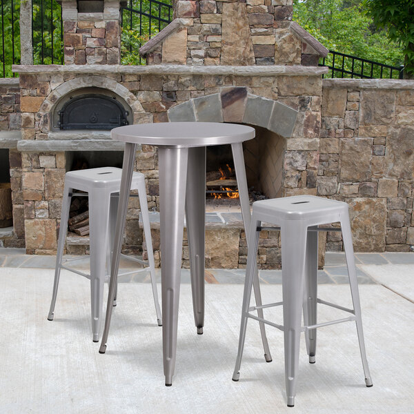 A Flash Furniture silver metal bar height table with two square seat backless stools on an outdoor patio.