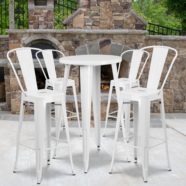A Flash Furniture white metal bar table with white stools around a fire.