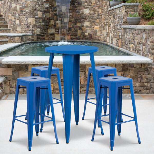 A Flash Furniture blue metal bar height table with 4 square seat backless stools on a blue table outside by water.