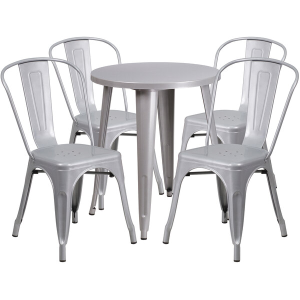 A round silver metal table with a white surface and four white metal chairs.