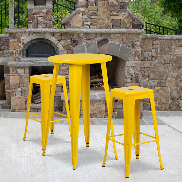 A yellow table with 2 yellow square seat bar stools.