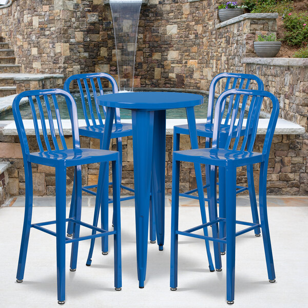 A blue metal Flash Furniture bar table with four blue chairs on a patio.