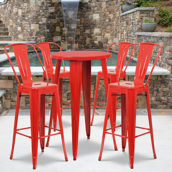 A Flash Furniture red metal table with 4 red stools on an outdoor patio.