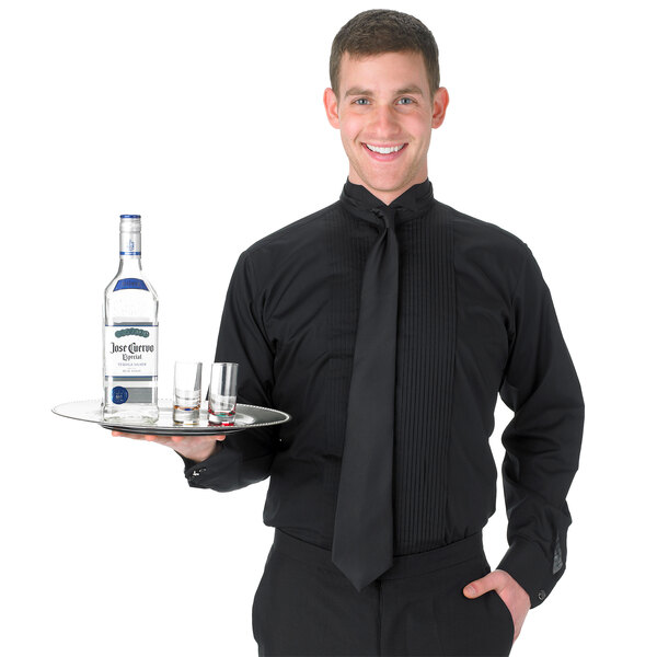 A man wearing a Henry Segal black tuxedo shirt with wing tip collar holding a tray with a bottle and shot glasses.