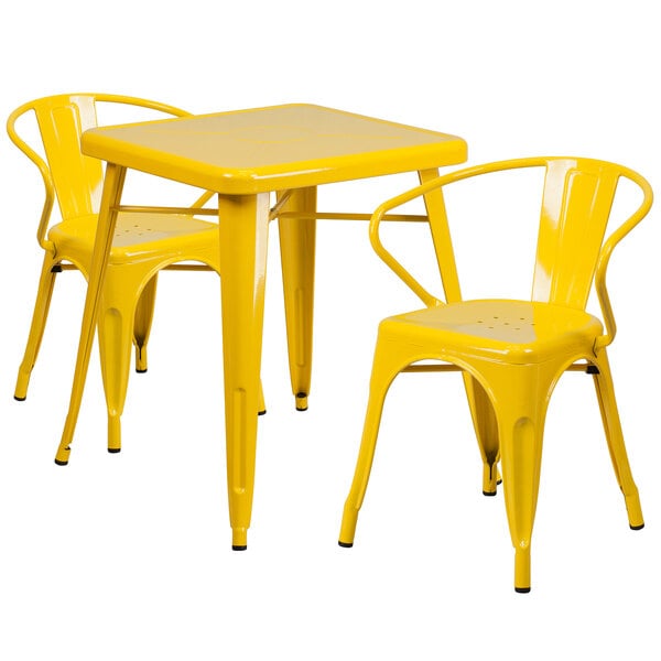 A yellow metal Flash Furniture table with 2 chairs on a outdoor patio.