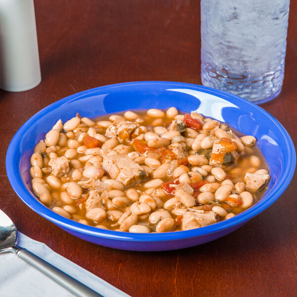A peacock blue melamine bowl filled with white beans and chicken.