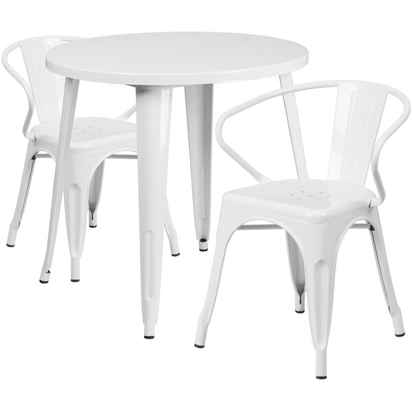 A round white metal table with two white metal arm chairs.