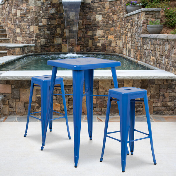 A blue metal table with two blue metal bar stools.