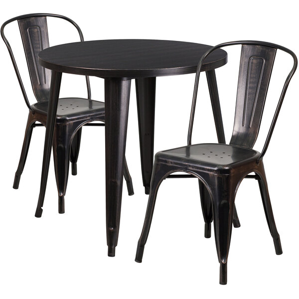 A black metal Flash Furniture table with black and antique gold metal chairs on either side.