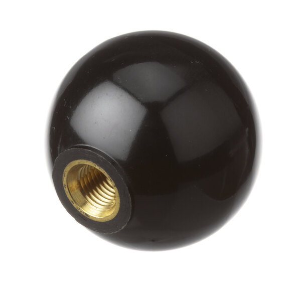 A close-up of a black round knob with a gold nut.