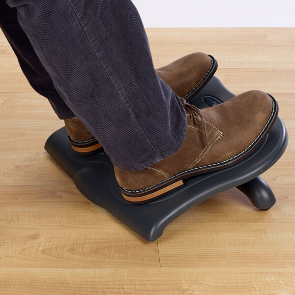 A person using a Kensington SoleSaver footrest with their feet on it.