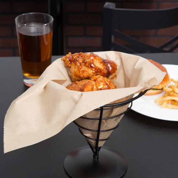 A wire cone basket lined with a Bagcraft Packaging EcoCraft Kraft paper bag holding fried chicken with a glass of beer.