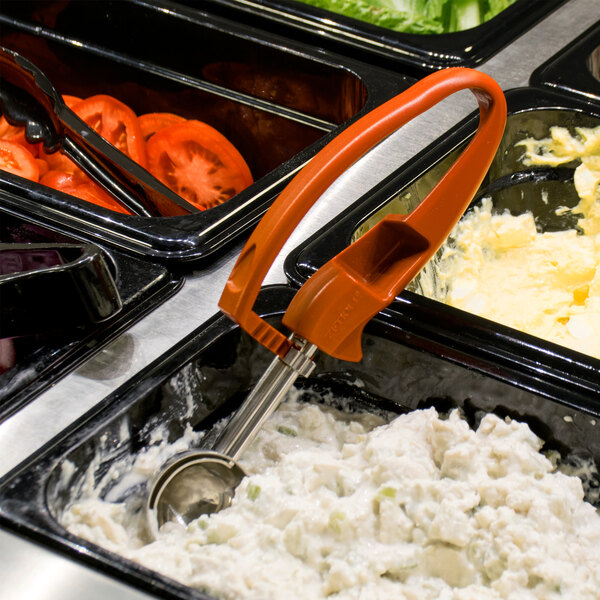 A tray of food with a Zeroll red universal EZ squeeze handle disher in it.