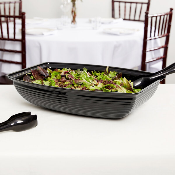A bowl of salad in a black Cambro rectangular ribbed bowl.
