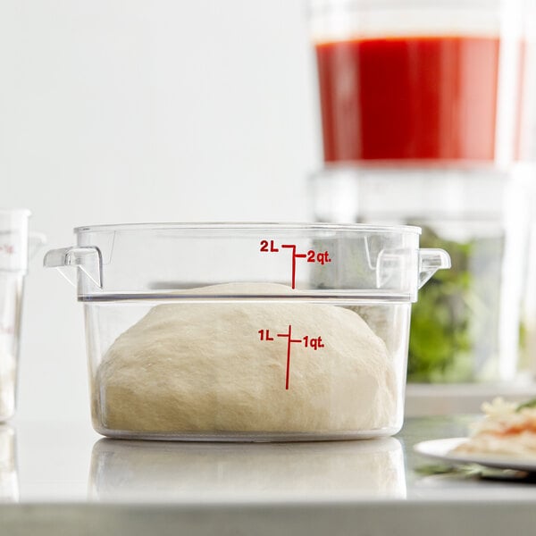 A clear plastic Cambro food storage container with pizza dough inside.