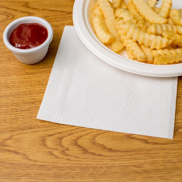 A plate of french fries and ketchup on a white napkin with a Choice white 1/4 fold luncheon napkin