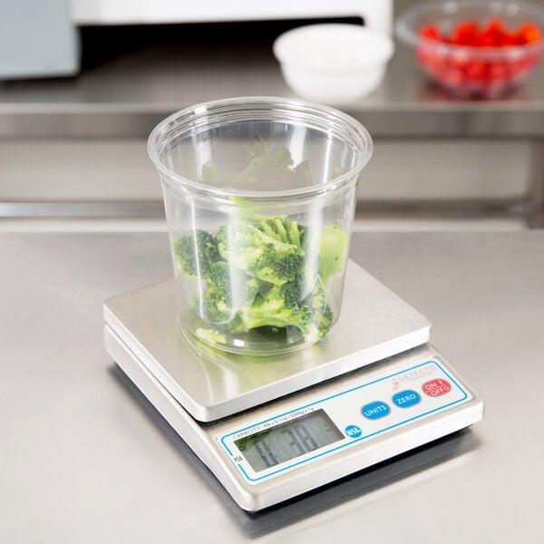 A Cardinal Detecto PS4 portion scale with a plastic container of broccoli on it.