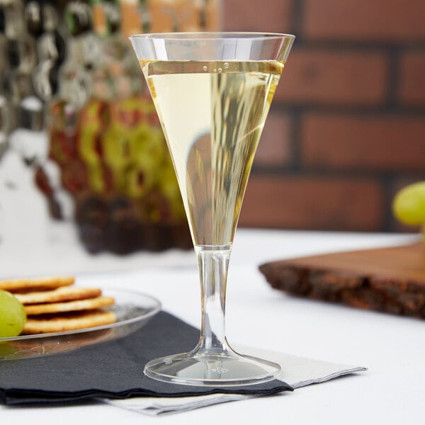 A clear Fineline Tiny Barware champagne flute filled with champagne on a table.