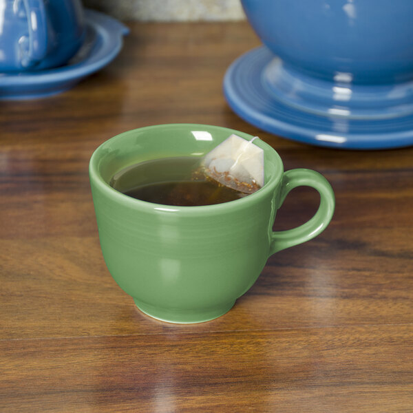 A green Fiesta china cup filled with tea and a tea bag.