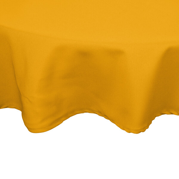 A gold poly/cotton blend round tablecloth on a white table.