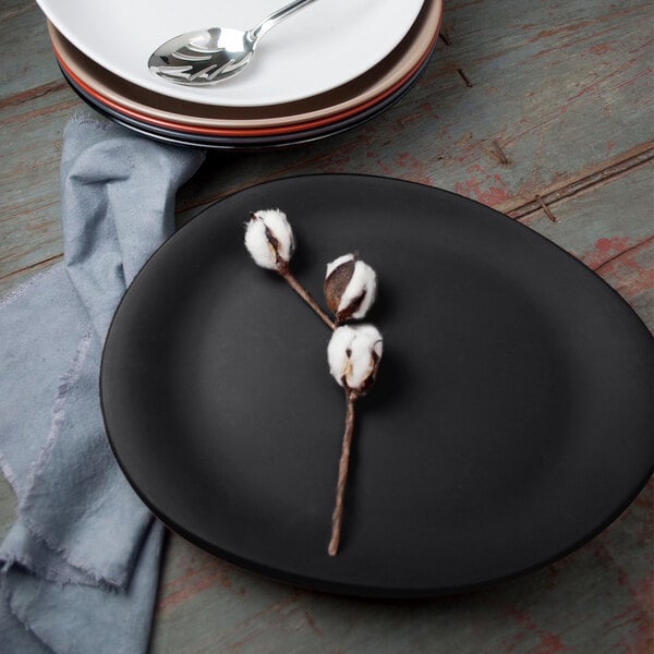 A black Libbey Driftstone melamine platter with a spoon on it.