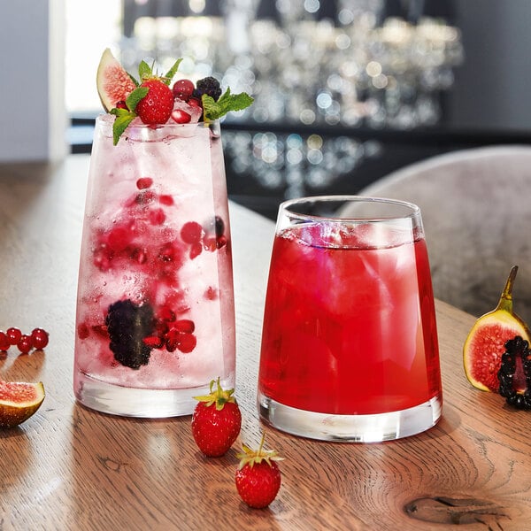 Two Chef & Sommelier Aska tumblers filled with red liquid, ice, and fruit on a table.