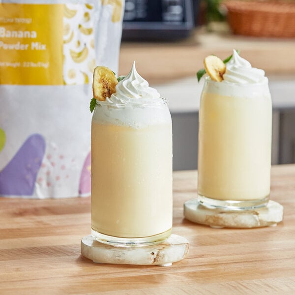 Two glasses of milkshakes with bananas and whipped cream made with Bossen Banana Powder Mix.