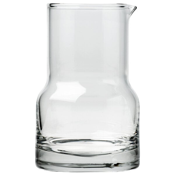 An Arcoroc clear glass side carafe with a small amount of liquid.