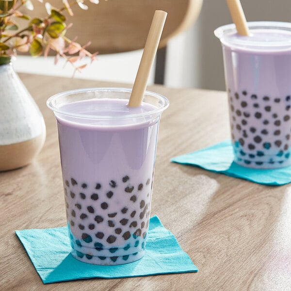 A couple of cups of bubble tea with straws on a table.