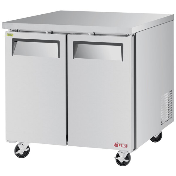 A silver Turbo Air undercounter freezer on wheels.
