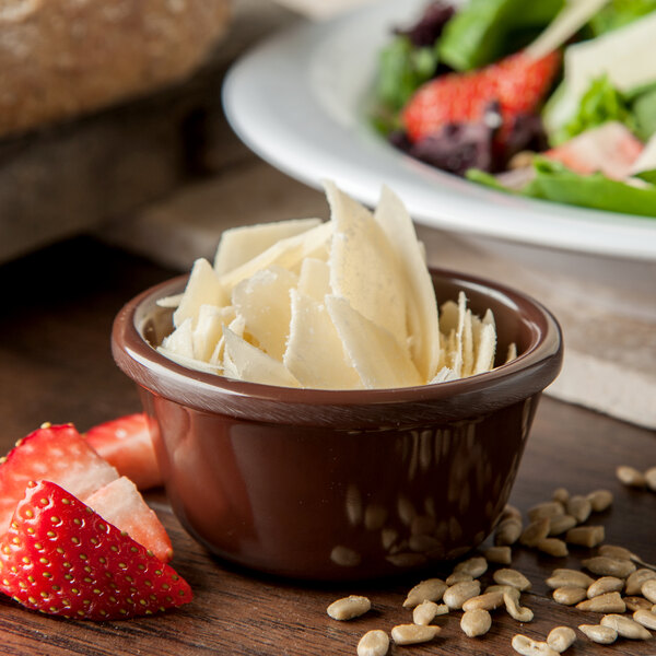 A Carlisle chocolate brown melamine ramekin filled with cheese next to a bowl of fruit and a salad.