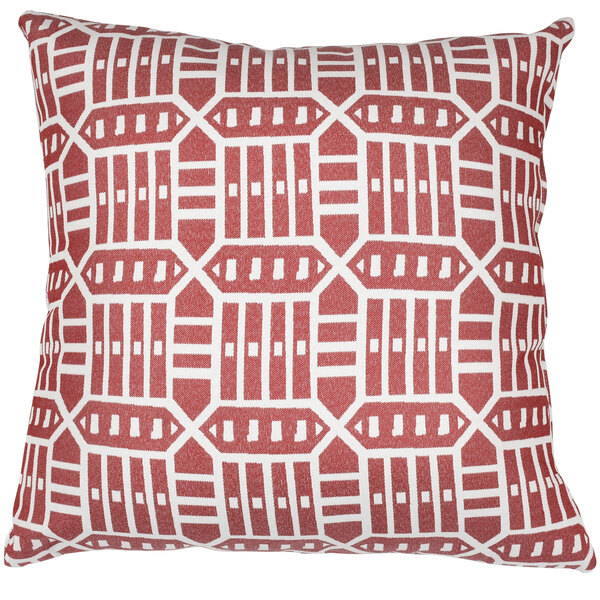 A red and white pillow with geometric patterns on a red outdoor lounge chair.