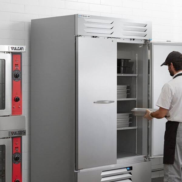 A man opening a Beverage-Air Vista Series reach-in refrigerator with solid doors.