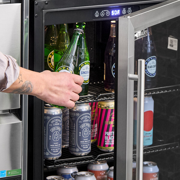 A glass door beverage cooler filled with assorted bottles and cans.