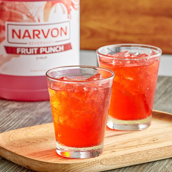 Two glasses of Narvon fruit punch with ice on a wooden table.