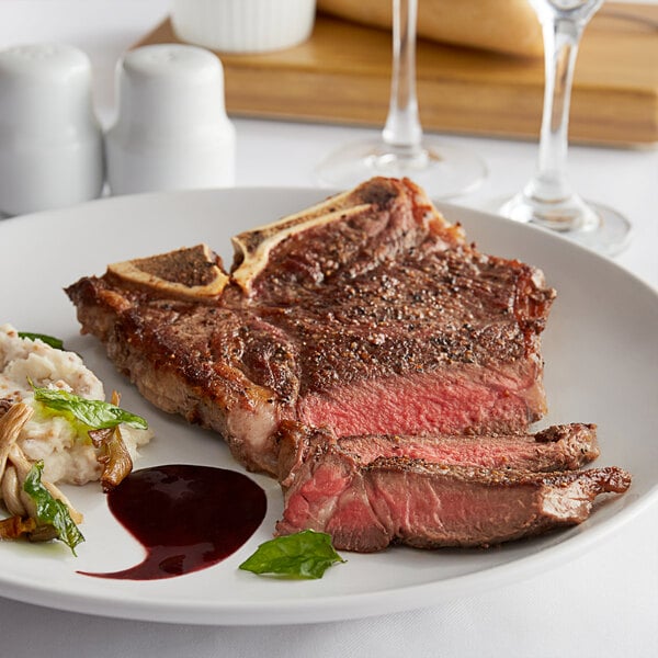 A Warrington Farm Meats T-Bone Steak on a plate with mashed potatoes and a glass of wine.