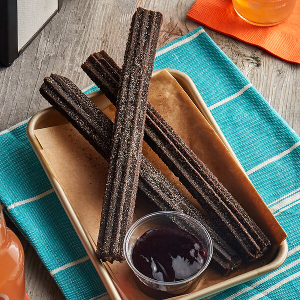 A tray of J & J Snack Foods Oreo Churros with sugar topping on a table with a cup of jam.