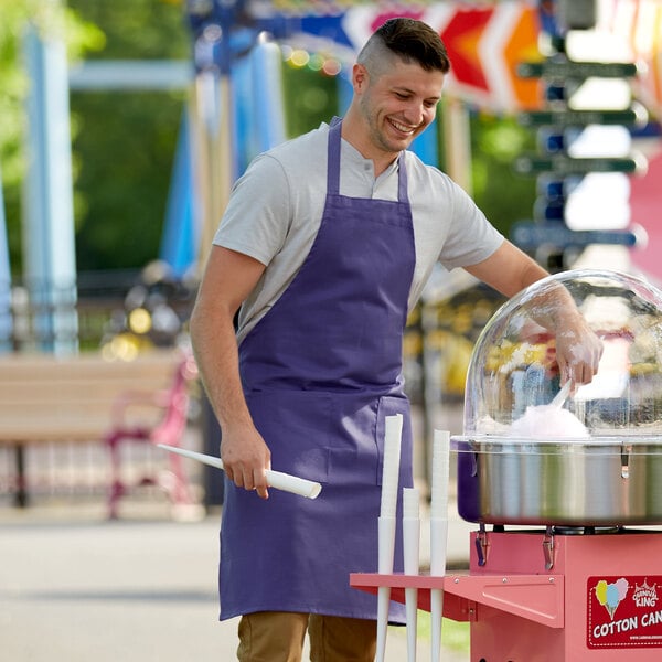 A man wearing a purple Choice bib apron holding cotton candy.