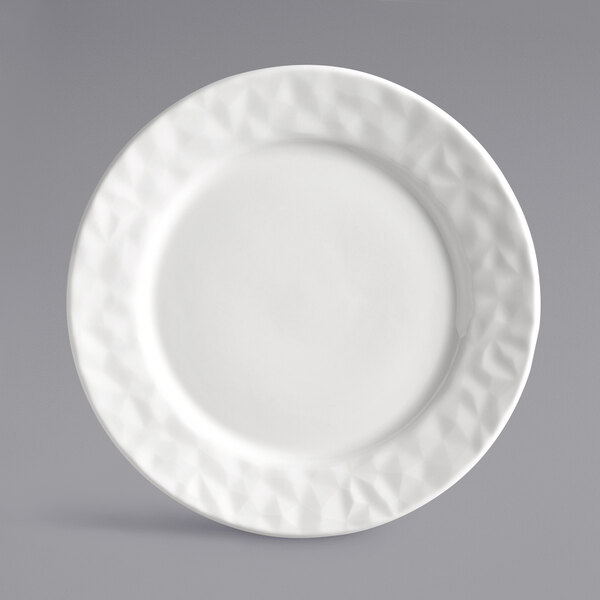 A close-up of a white Reserve by Libbey Royal Rideau porcelain plate with a diamond patterned wide rim.