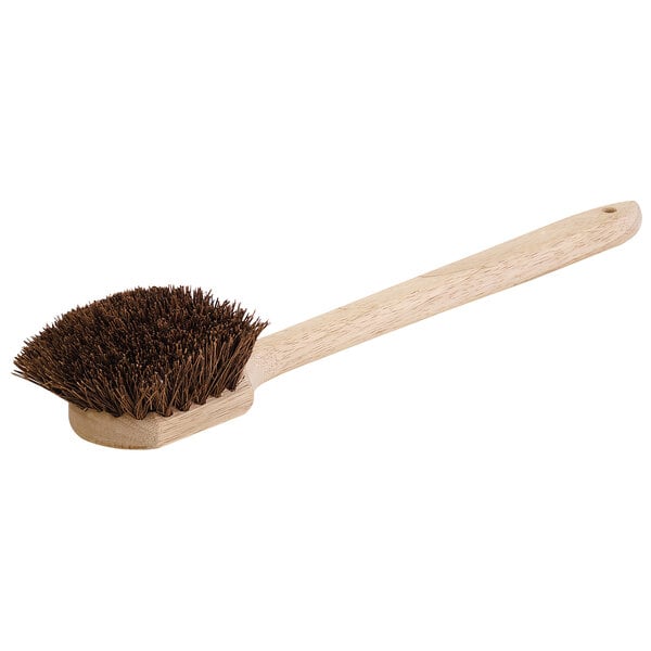 A Carlisle Sparta wok and griddle brush with a wooden handle and palmyra bristles.